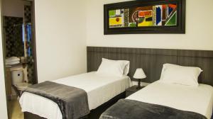 Hotel Viña Del Mar في سانتا مارتا: غرفة نوم بسريرين وصورة على الحائط