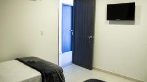 Habitación con cama y puerta con TV en Hotel Viña Del Mar, en Santa Marta