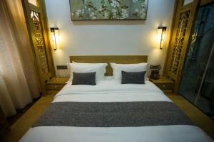 a bedroom with a large white bed with two pillows at Home of heart Inn in Zhangjiajie