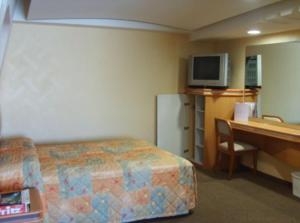 a hotel room with a bed and a desk with a computer at Hotel Terminal de Puebla in Puebla