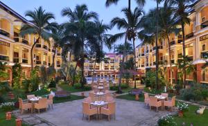 a courtyard with tables and chairs and palm trees at Country Inn & Suites by Radisson, Goa Candolim in Candolim