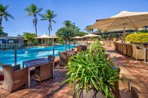 een resort met een zwembad en tafels en stoelen bij Karratha International Hotel in Karratha