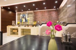 a kitchen with a table with pink flowers in a vase at Metropolo Jinjiang Xuzhou Railway Station Suning Plaza Chudu in Xuzhou