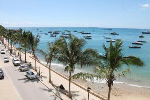 a beach with palm trees and boats in the water at Mizingani Seafront Hotel in Zanzibar City