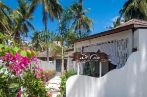 龍目島的住宿－De'Coco Villa，棕榈树建筑前的标志