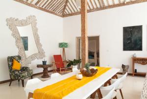 a dining room with a yellow table and chairs at De'Coco Villa in Gili Air