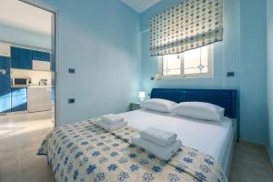 een blauwe slaapkamer met een bed met handdoeken erop bij Stella Beach House in Archangelos