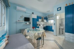 een blauwe kamer met een tafel en een keuken bij Stella Beach House in Archangelos