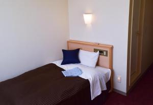 una camera da letto con un letto con una camicia blu sopra di Hotel All In Stay Hakodate a Hakodate