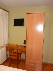 a room with a desk and a cabinet and a television at Hostal Donaire in Tomelloso