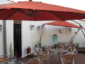 un patio con mesas y sillas y sombrillas rojas en Hostal Donaire, en Tomelloso