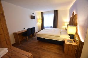 a hotel room with a bed and a table and a desk at Hotel Nès Crépes in Pozza di Fassa