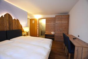 a bedroom with a bed and a desk and a table at Hotel Nès Crépes in Pozza di Fassa