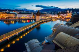 a city with a bridge over the water at night at Hotel Des Alpes in Lucerne