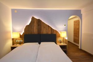 a bedroom with a large bed with two tables and two lamps at Hotel Nès Crépes in Pozza di Fassa