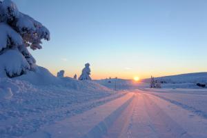 een persoon die bij zonsondergang over een met sneeuw bedekte weg loopt bij Pellestova Hotell Hafjell in Hafjell