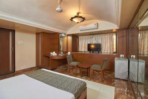 a bedroom with a bed and a desk and a tv at Yogi Broadway in Mumbai