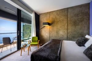 a bedroom with a large bed and a large window at Boutique & Design Hotel Navis - Small Luxury Hotels of the World in Opatija