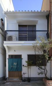 een wit gebouw met een balkon en een deur bij Chikyuutabikazoku USJ in Osaka