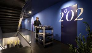 a woman standing at a table in a blue room at Boutique & Design Hotel Navis - Small Luxury Hotels of the World in Opatija