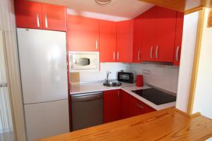 ラ・マタにあるParque Mar Apartment 4269の小さなキッチン(赤いキャビネット、白い冷蔵庫付)