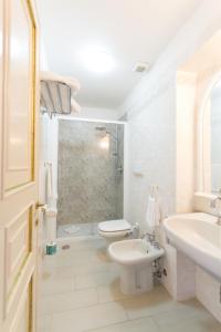 La salle de bains blanche est pourvue de toilettes et d'un lavabo. dans l'établissement Villa Parisi Grand Hotel, à Castiglioncello