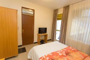 a bedroom with a bed and a tv and a window at Anthurium Residential Hotel in Kigali