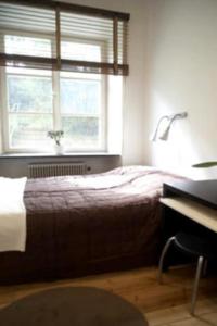 een slaapkamer met een bed, een bureau en een raam bij Stockholm Checkin Apartment Fridhemsplan in Stockholm
