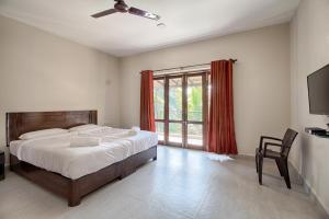 a bedroom with a bed and a television and a window at Iora Baga Beach in Baga