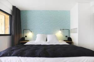 a bedroom with a bed with a blue wall at Dormir sur la Plage in Marennes