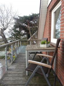 a wooden deck with a table and chairs on a porch at Strandhaus Buchtmitte in Haffkrug