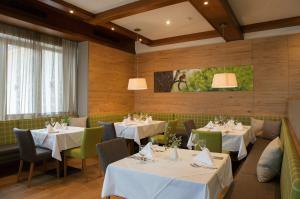 a restaurant with white tables and green chairs at Naturhotel Bauernhofer in Heilbrunn