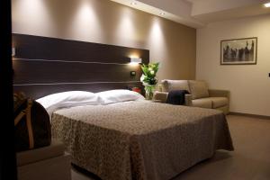 um quarto com uma cama grande e uma cadeira em Hotel La Conchiglia em Romano di Lombardia