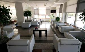 un vestíbulo con sofás blancos y mesas en un edificio en Hotel Adelma, en Hoznayo