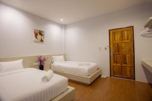 a bedroom with two beds and a wooden door at Lin House in Thalang