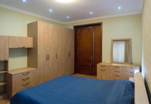 a bedroom with a blue bed and wooden cabinets at Lagidze Apartment in Tbilisi City