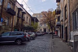 a cobblestone street with parked cars and buildings at Lagidze Apartment in Tbilisi City