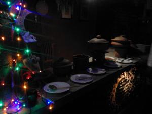 Habitación oscura con luces de Navidad y platos en una mesa en Sihilro Regency, en Udawalawe