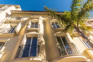 a white building with balconies and a palm tree at Résidence Villa d'Elsa in Juan-les-Pins