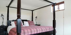 a bedroom with a four poster bed with a plaid blanket at Drovers Rest Farm Stay in Hay-on-Wye +74 photos