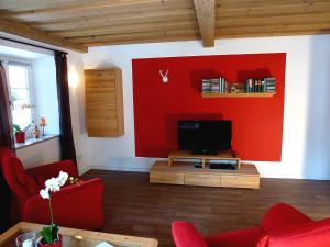 a living room with a red wall and a tv at Haus Irlinger in Schönau am Königssee