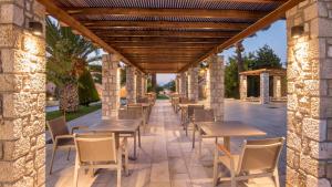 
a patio area with tables, chairs and umbrellas at Horizon Beach Resort in Mastihari
