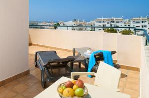 a balcony with a table and chairs and a bowl of fruit at Oceanus Aparthotel in Albufeira