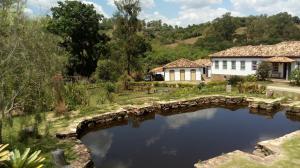 a bridge over a pond in front of a house at Hotel Fazenda Palestina in Itapecerica