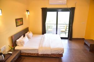 a bedroom with a large bed and a balcony at Nature Trails Kundalika, Kolad in Kolād