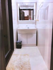 a white bathroom with a sink and a mirror at Osaka Sinsei Guest House in Osaka