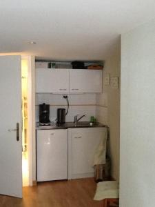 una cocina con armarios blancos y fregadero en Agora Mijo Chambre d'Hôtes, en Nantes