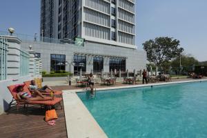 a woman sitting in a chair next to a swimming pool at President Hotel at Umodzi Park in Lilongwe