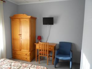 een slaapkamer met een bureau, een stoel en een kast bij Hostal Donaire II in Tomelloso