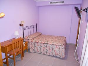Habitación pequeña con cama y escritorio. en Hostal Donaire II, en Tomelloso